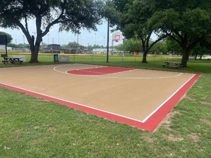 Newly resurfaced multipurpose court with vibrant color coating, black square net posts, and a durable Novacushion base