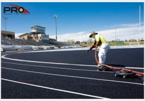 Pro Track & Tennis crew member applying surface material to a running track during installation.