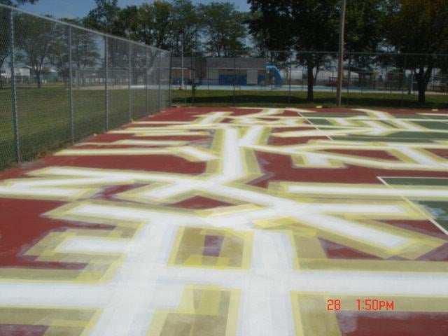 In-progress tennis court resurfacing by Pro Track and Tennis, showing partially prepared surfaces and construction materials on site.
