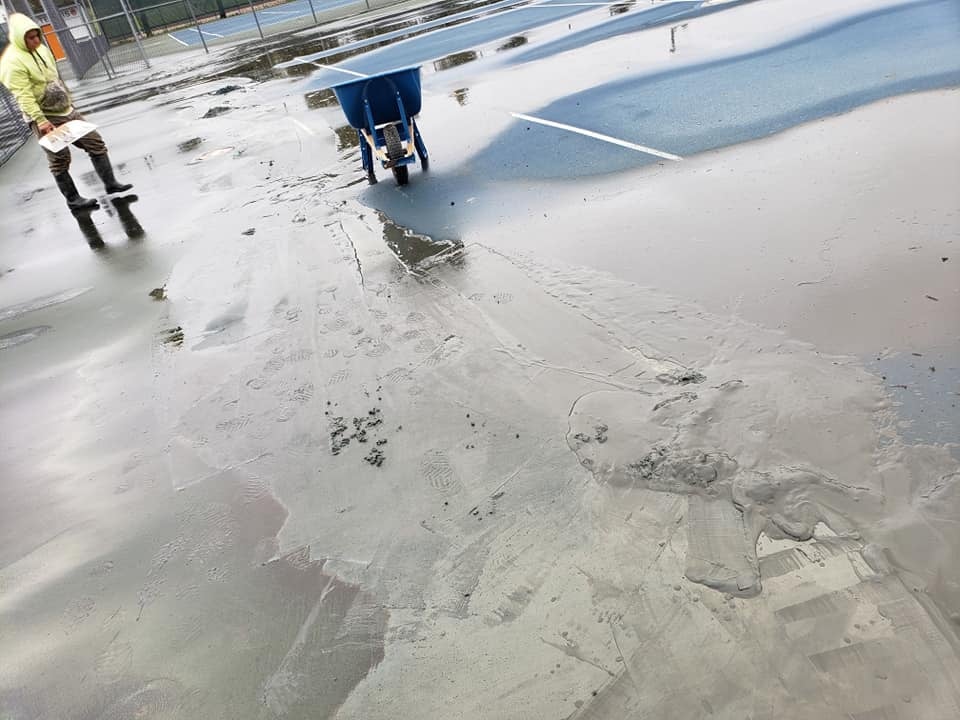 Pro Track and Tennis team actively working on a tennis court resurfacing project, preparing and restoring the surface for improved playability and safety.