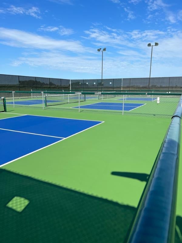 Side view of a fenced-in pickleball court with net installed
