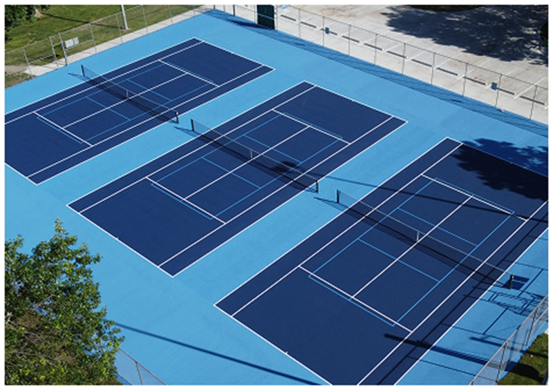Aerial view of three resurfaced outdoor tennis courts with dark blue acrylic playing areas and light blue perimeter