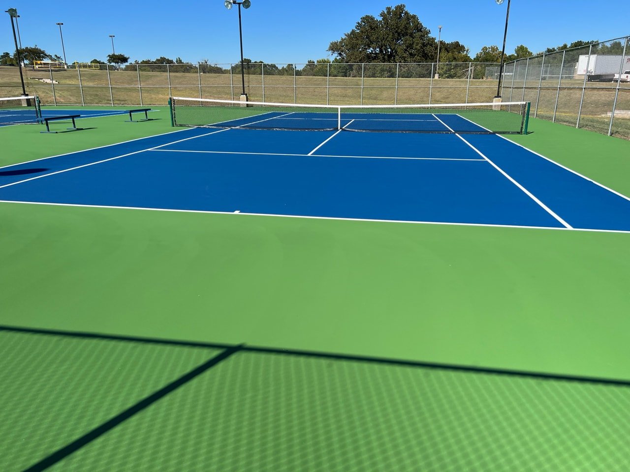 Resurfaced outdoor tennis courts with bright blue and green colors