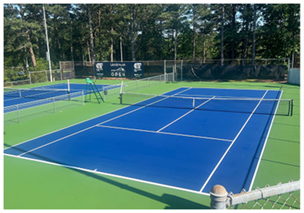Resurfaced blue tennis courts with green perimeter showing seamless surface application