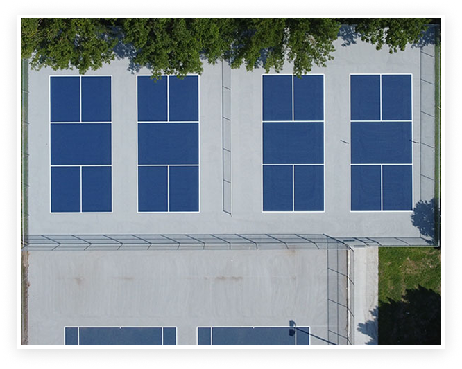 Aerial view of multiple blue pickleball courts with white line markings and surrounding fencing