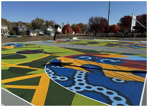 Multi-purpose court resurfacing and community park investment project by Pro Track & Tennis Colorful multi-purpose court with artistic surface mural and basketball hoops in a community park setting