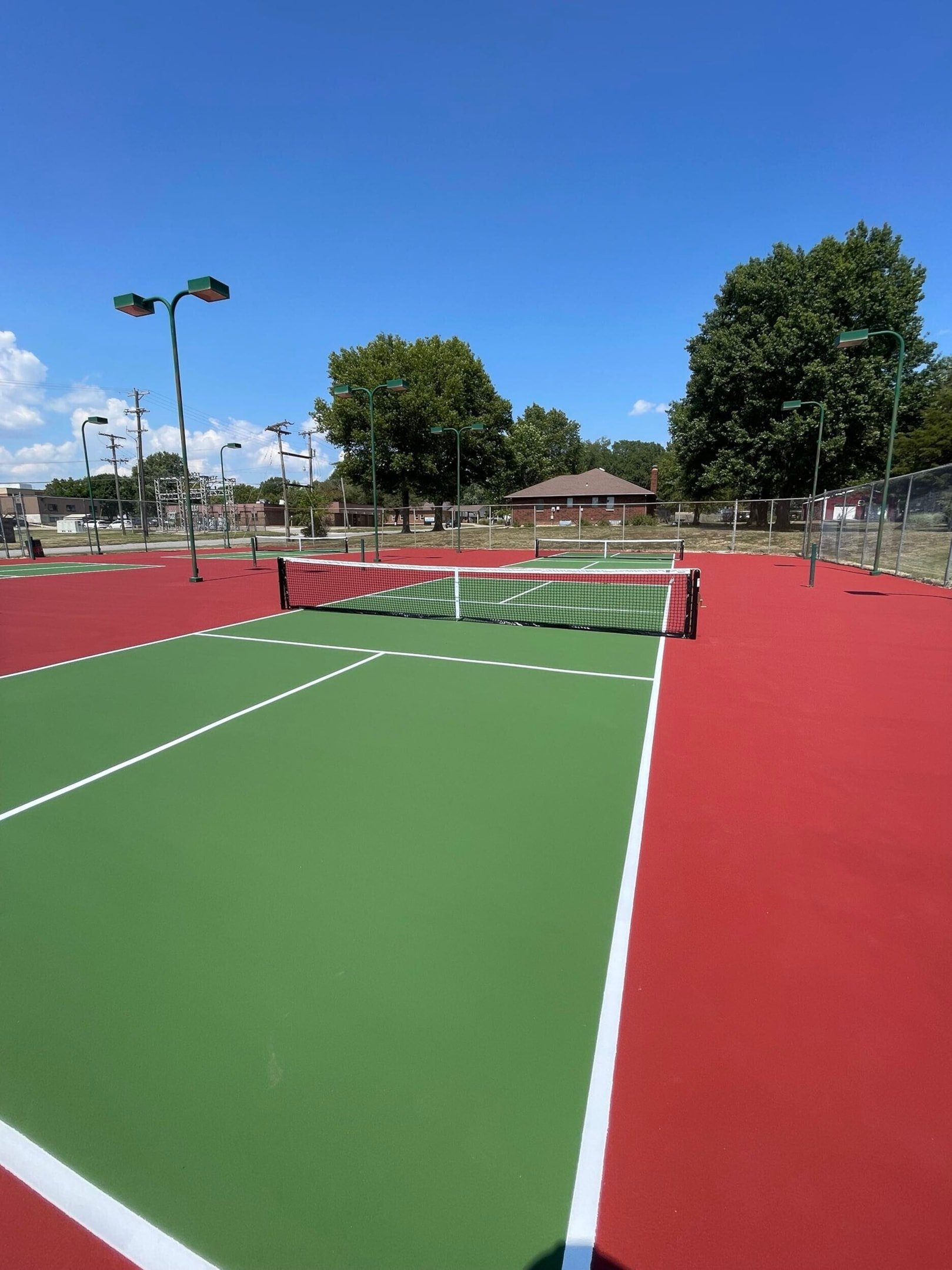 Completed UV-resistant tennis court resurfacing with red and green color coating for enhanced durability and appearance.