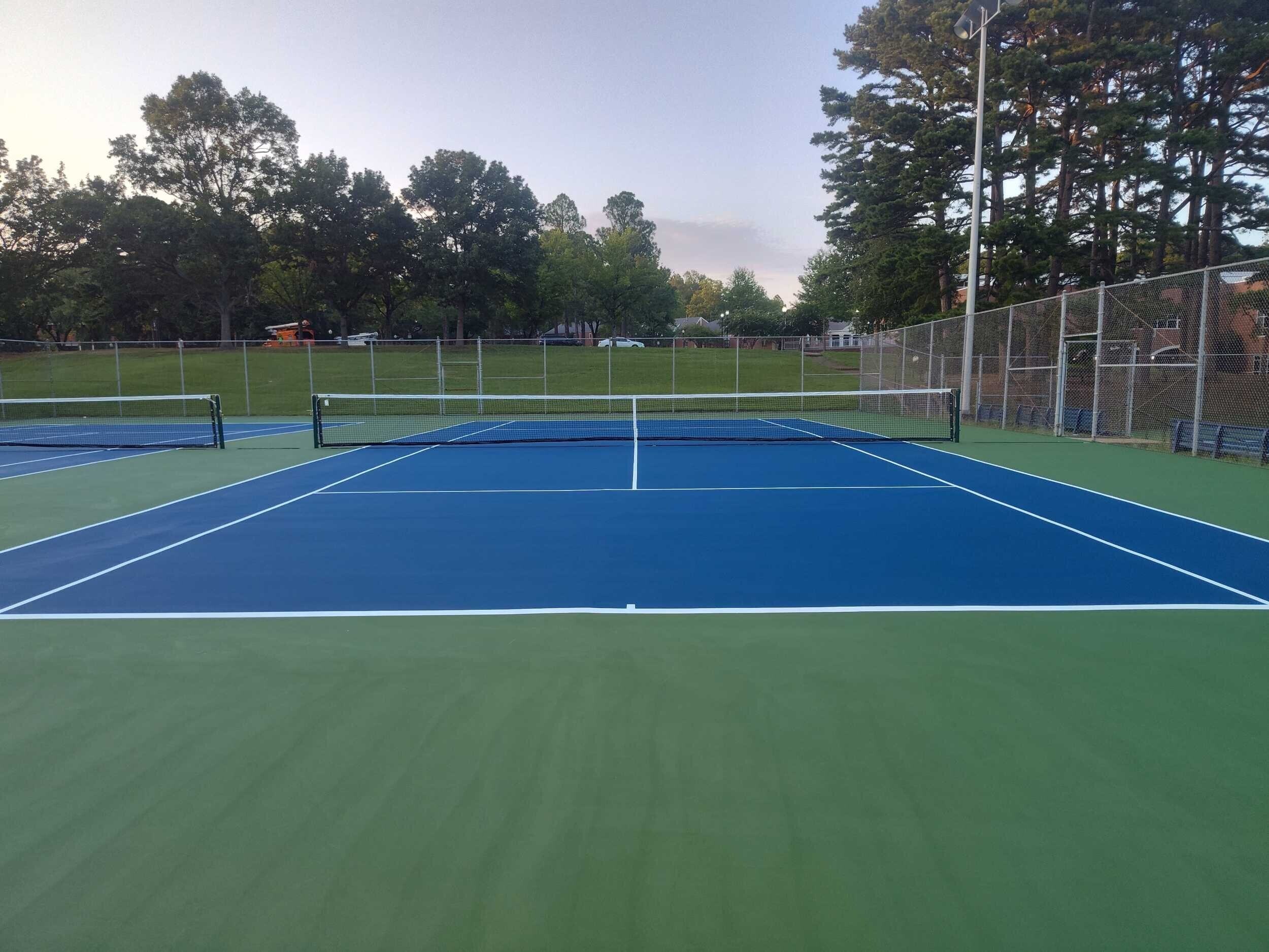 Completed UV-resistant tennis court resurfacing with vibrant blue and green acrylic coating for long-lasting color protection