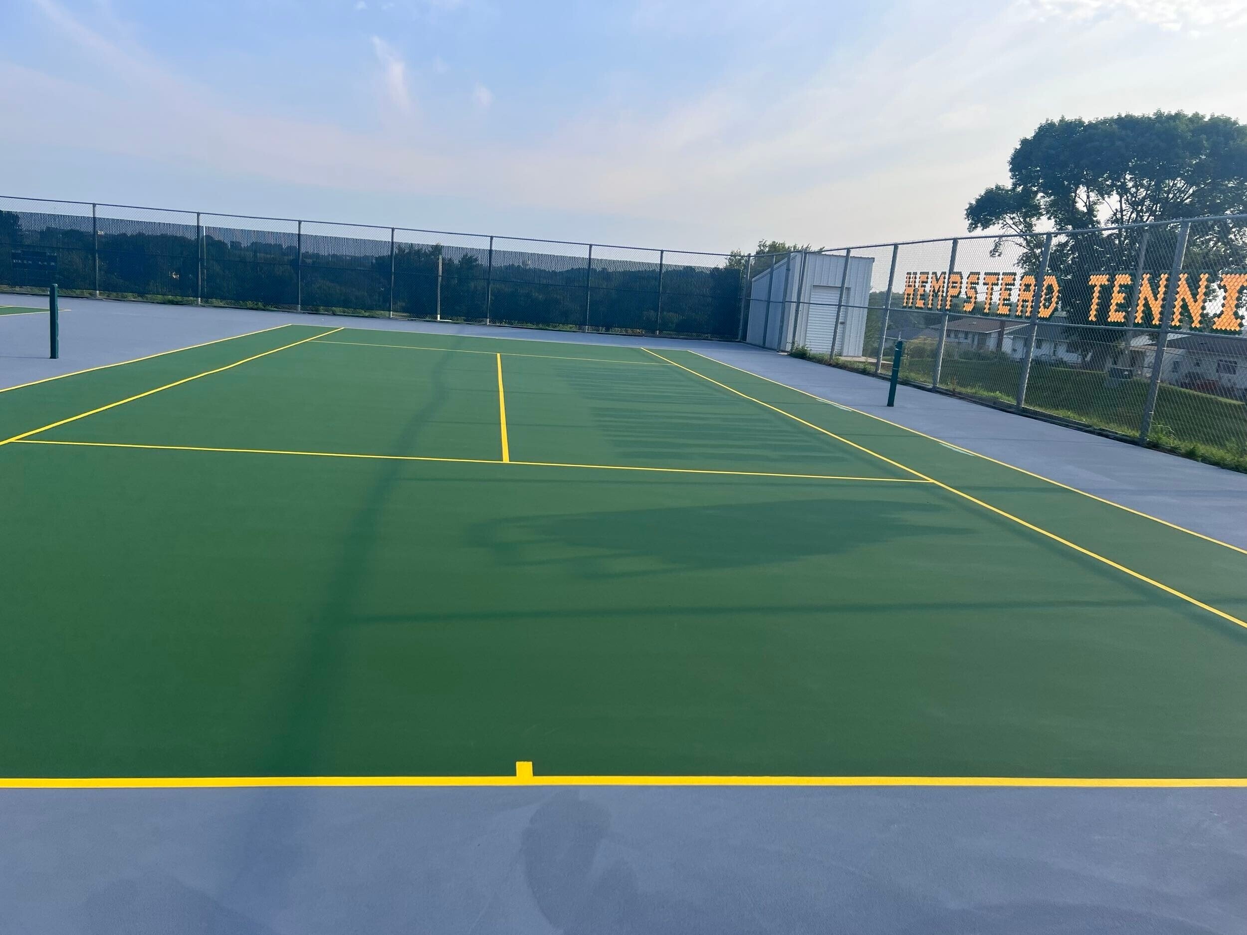 Completed tennis court resurfacing with proper slope correction and new color coating for long-term drainage performance.