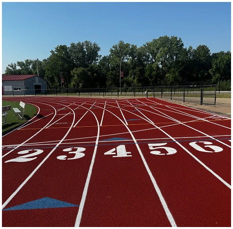 Newly built red running track in Georgia with white lane markings surrounded by trees and field area
