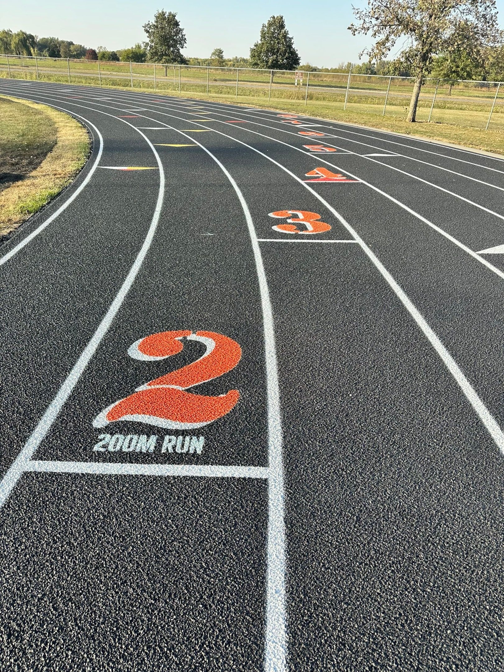 Running track with fresh lane numbers and 200m start markings in bright orange.