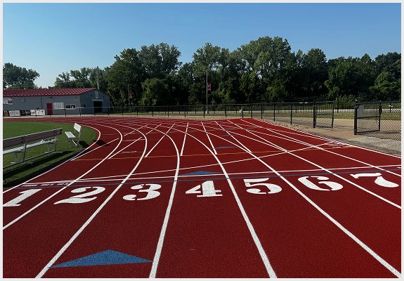 Red running track with fresh lane numbers and clear white striping at a school facility.