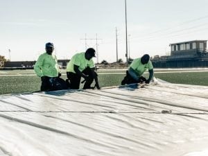 Professional running track contractors reviewing surface conditions during a track maintenance project.