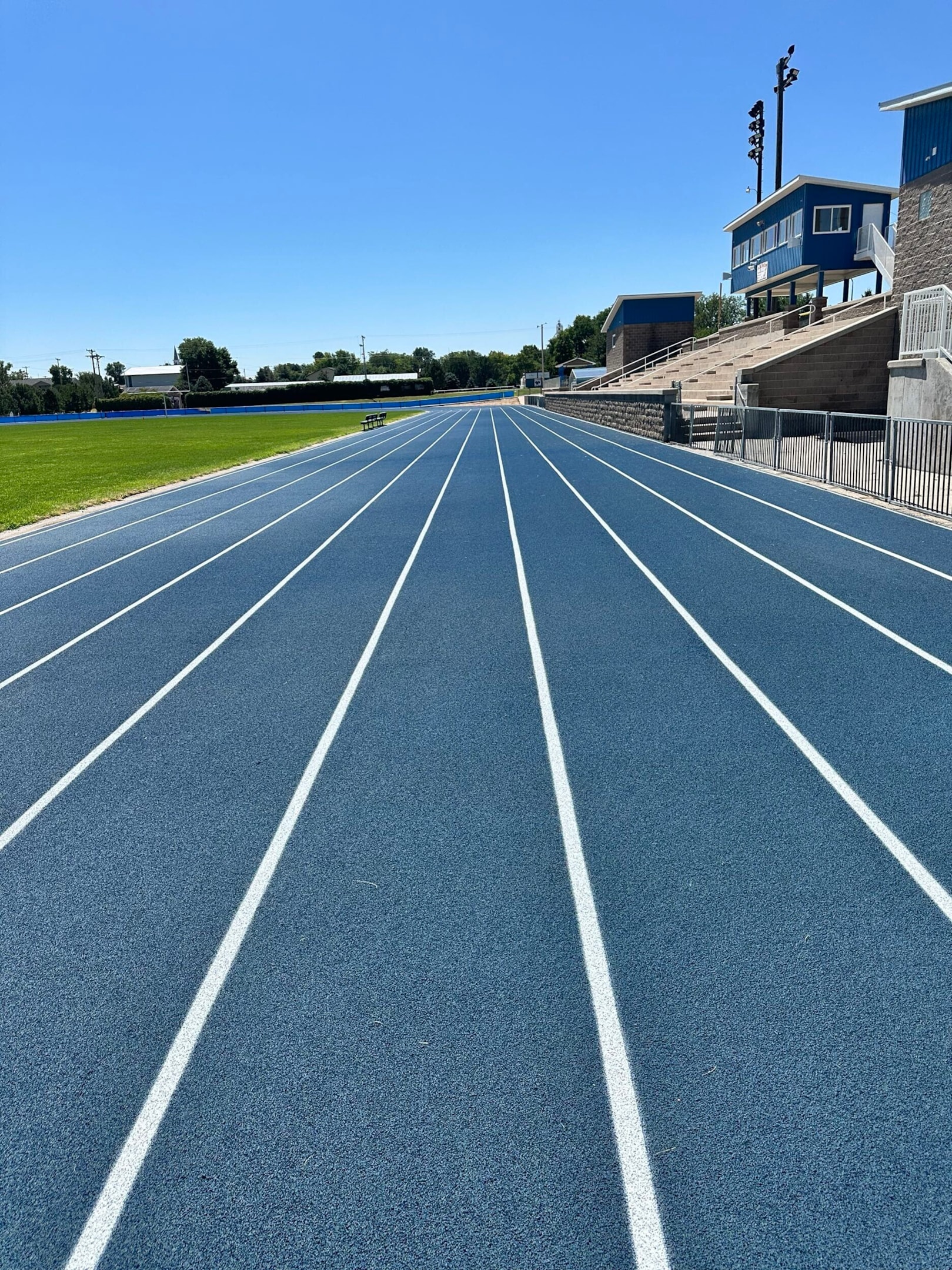 Newly resurfaced running track with blue rubber surface and clean lane lines, used to illustrate track resurfacing vs rebuild decisions.