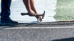 Professional running track contractor checking surface quality before installing the next layer.