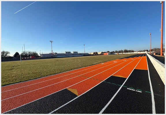 Newly resurfaced running track showing vibrant lanes and smooth rubber surface beside the field.