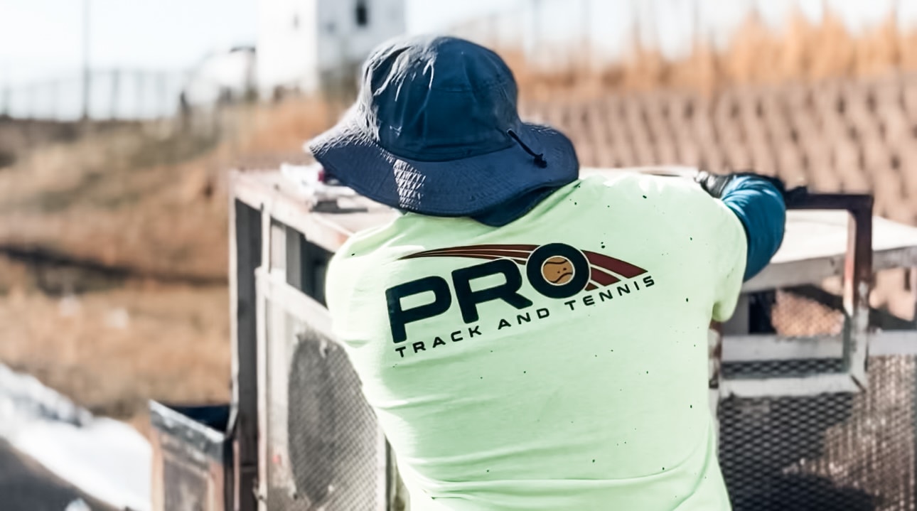 Pro Track & Tennis crew member operating resurfacing equipment during a rubber running track installation.