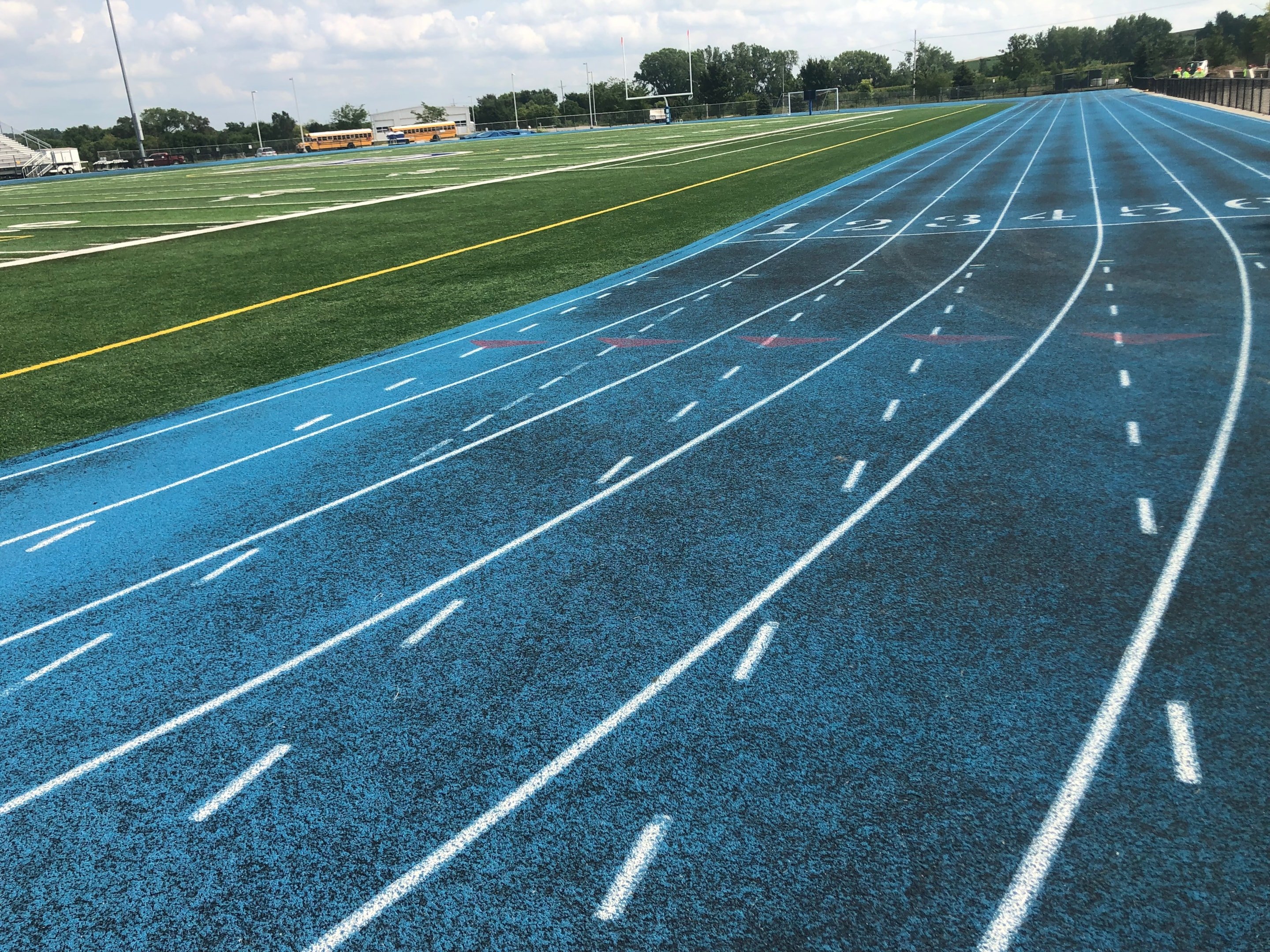 Blue running track with visible surface wear and fading lanes, showing early signs of running track cracks and track surface issues