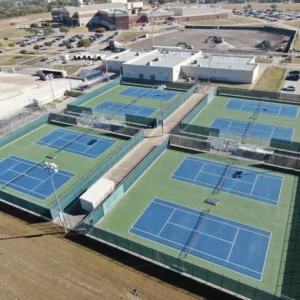 Wide aerial view of the Red Oak High School tennis complex showing multiple courts, fencing, and surrounding campus