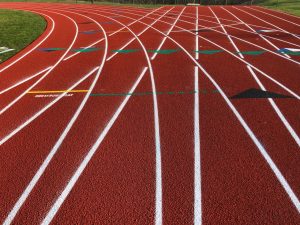 Red running track curve with white lane markings and staggered start lines.