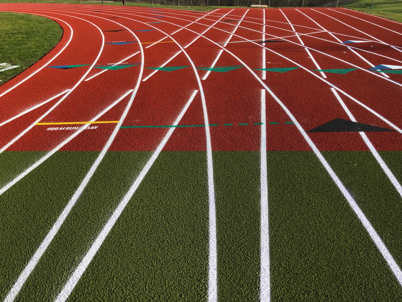Curved section of a red outdoor running track with clearly marked lanes.