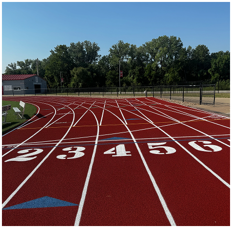 Red synthetic running track with clearly marked lanes at a school athletic facility.