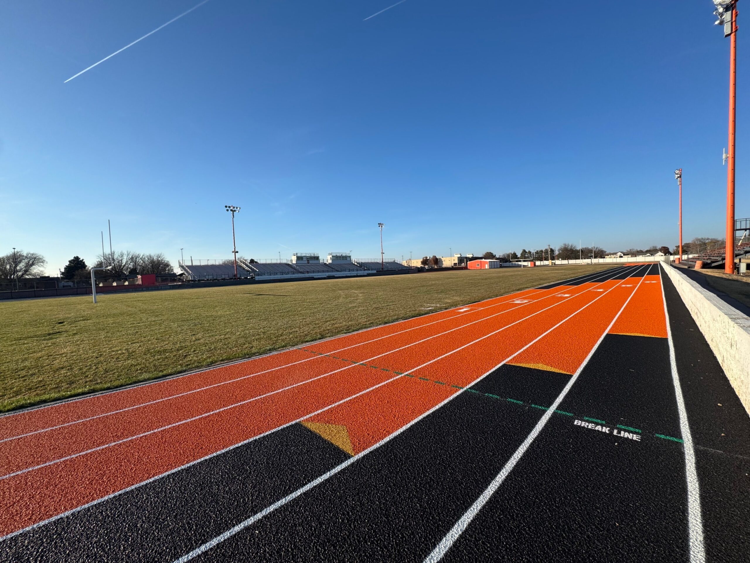 Wide view of a synthetic running track with relay exchange zone markings, similar to a Mondo track system.