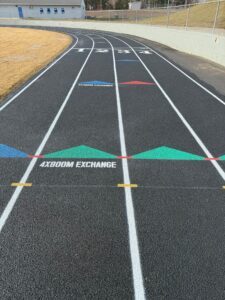 Newly resurfaced running track with lane markings and colored exchange zone arrows.