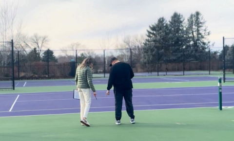 Athletic Director’s Guide to Tennis Court Budget Approval Athletic director inspecting school tennis court surface during budget planning evaluation