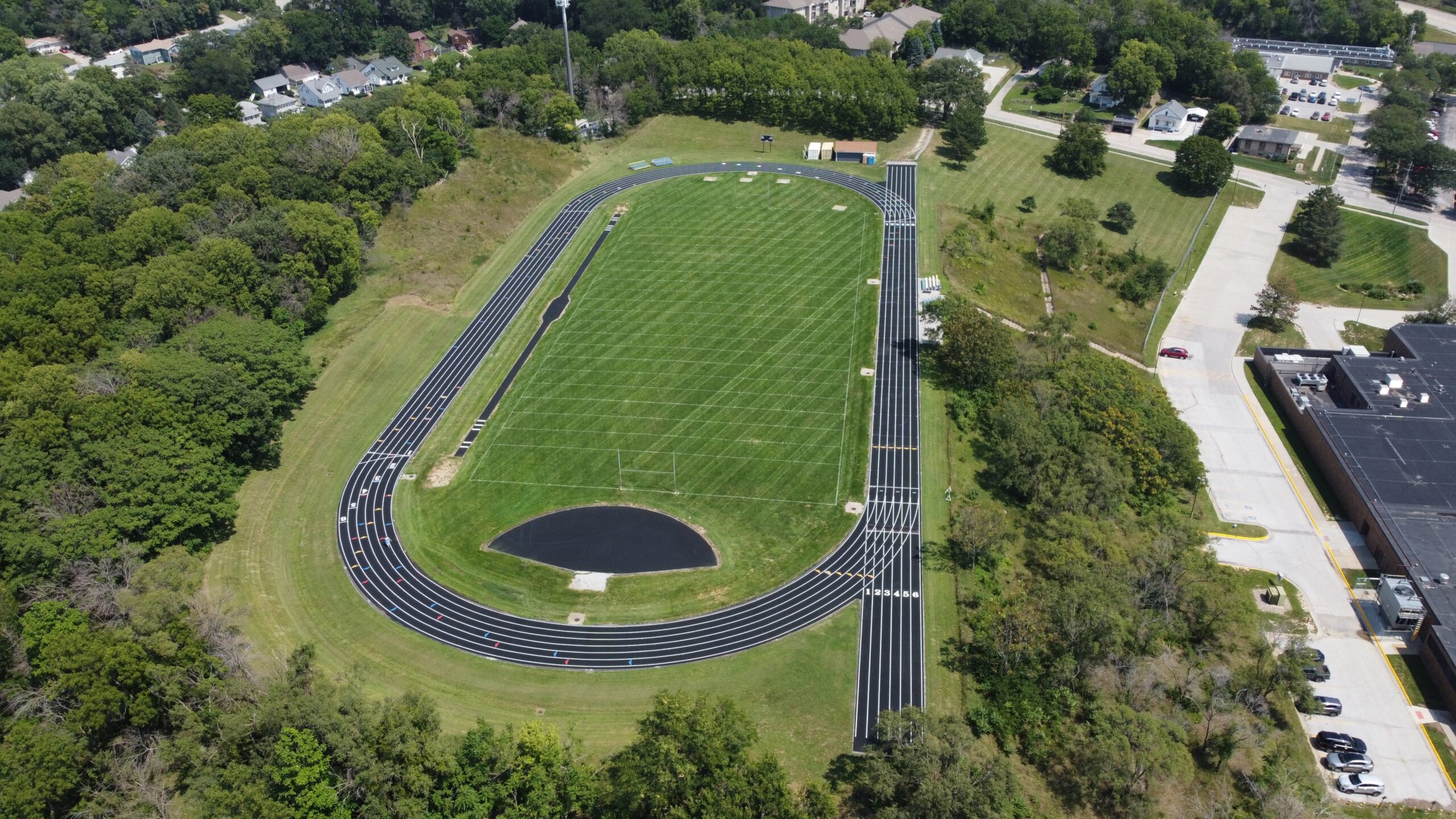 Aerial view of a high school running track and football field with a synthetic track surface similar to a Mondo track system.