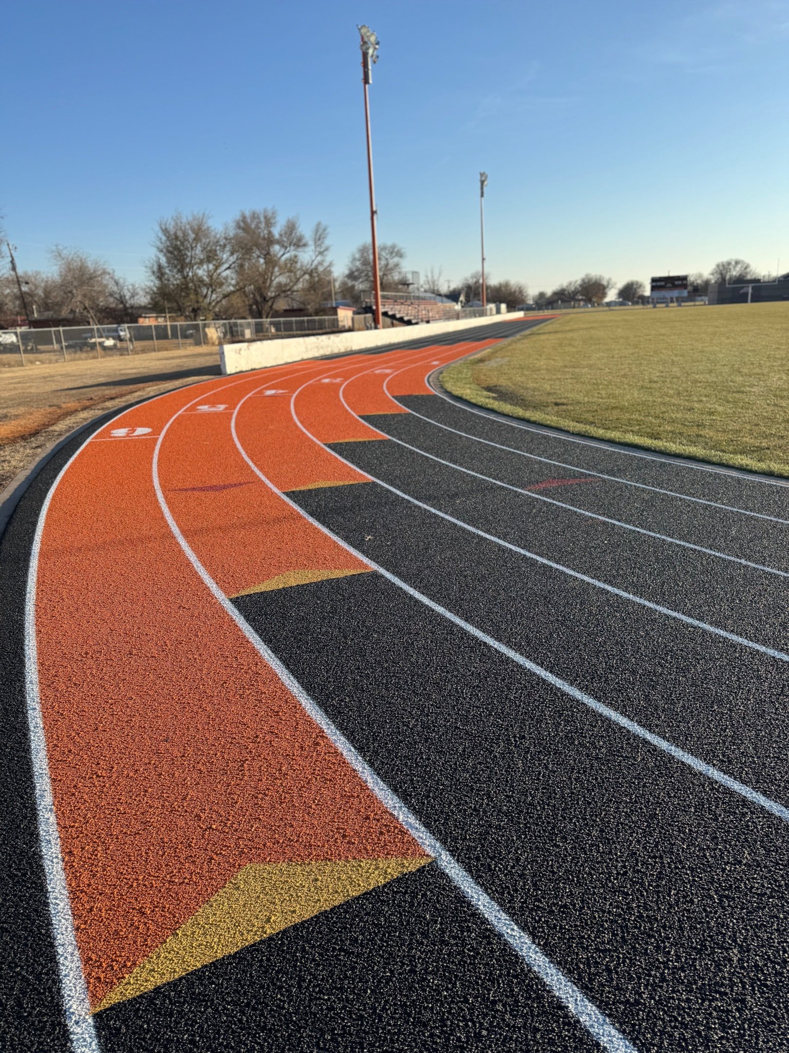 Curved section of an outdoor running track with lane markings showing standard track layout at a school athletics facility