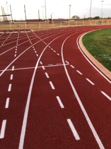 Red running track surface with lane markings for warranty and maintenance planning.