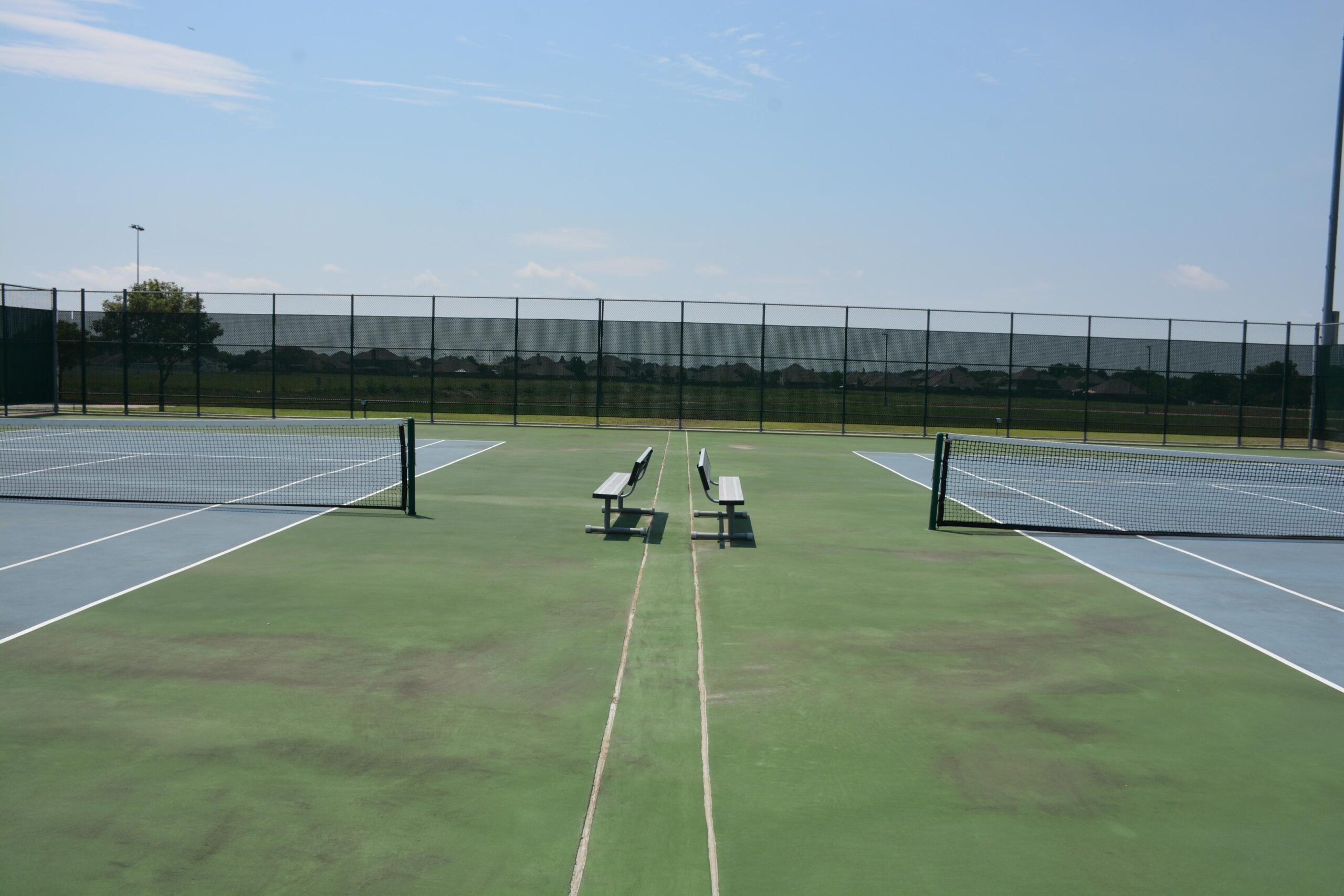 Aging tennis courts showing surface wear used for realistic resurfacing project budgeting