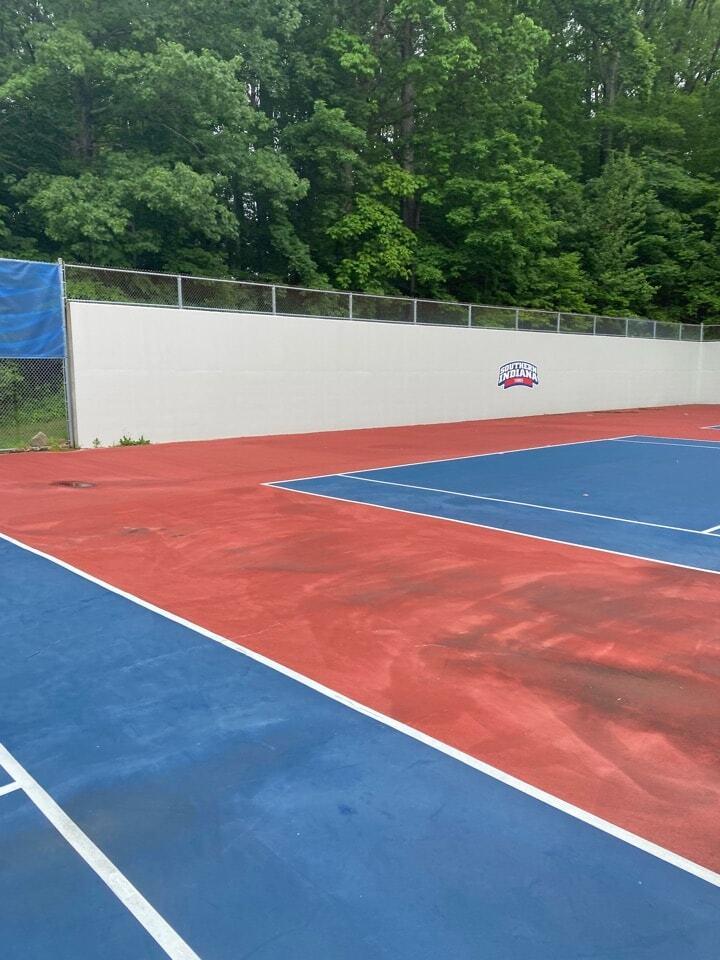 Tennis court surface showing staining and moisture buildup in a humid environment affecting ability to extend tennis court lifespan