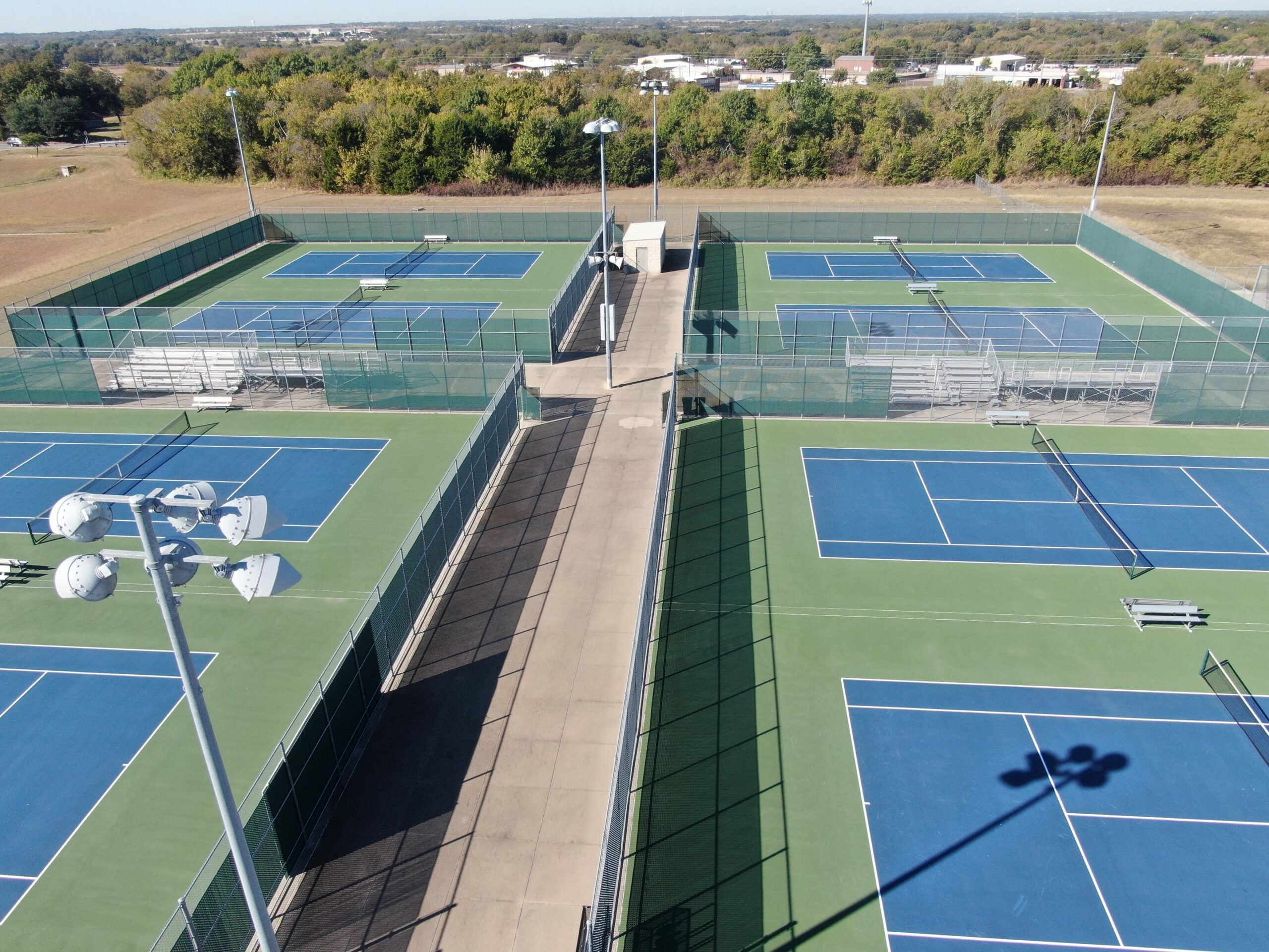 Aerial view of multiple outdoor tennis courts showing clean surfaces and layout to extend tennis court lifespan