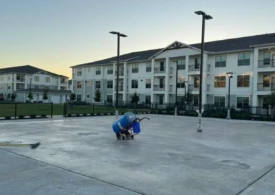 Acrylic sport surface coating application in progress on residential pickleball courts at dusk in Baytown, Texas