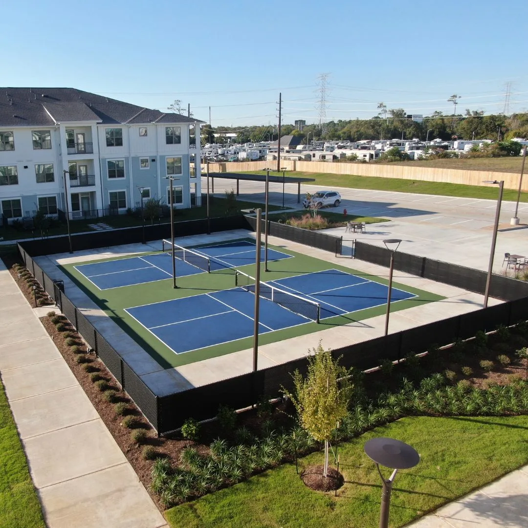 Completed outdoor pickleball courts at a residential community in Baytown, TX showing finished acrylic surface and perimeter fencing