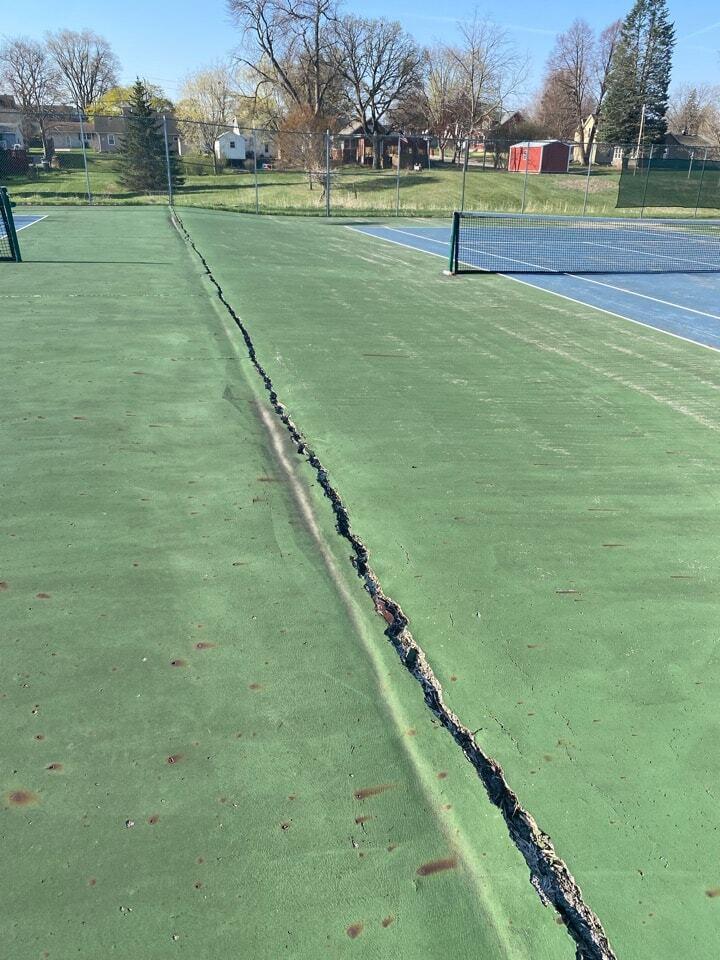 Large structural crack in tennis court surface showing base movement that limits ability to extend tennis court lifespan