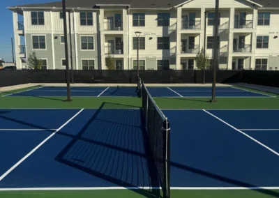Outdoor residential pickleball courts in Baytown, TX with blue and green two-tone surface and net posts installed by Pro Track and Tennis