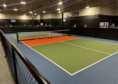 ndoor pickleball court with green and orange surface coating and portable net installed by Pro Track and Tennis