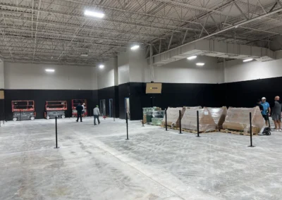 Indoor tennis court construction in progress with net posts set and surface materials staged on pallets