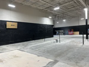 Concrete surface preparation and net post installation during indoor tennis court build out