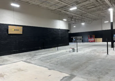 Concrete surface preparation and net post installation during indoor tennis court build out