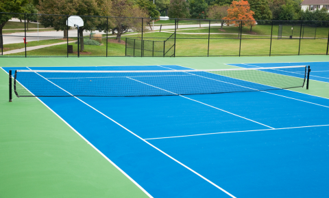 Tennis Court Surface and Net at Multi-Court Facility Blue tennis court surface with green surrounds and net at a multi-court facility
