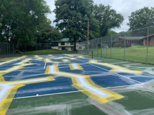 Tennis court crack repair preparation with marked surface areas for renovation planning.