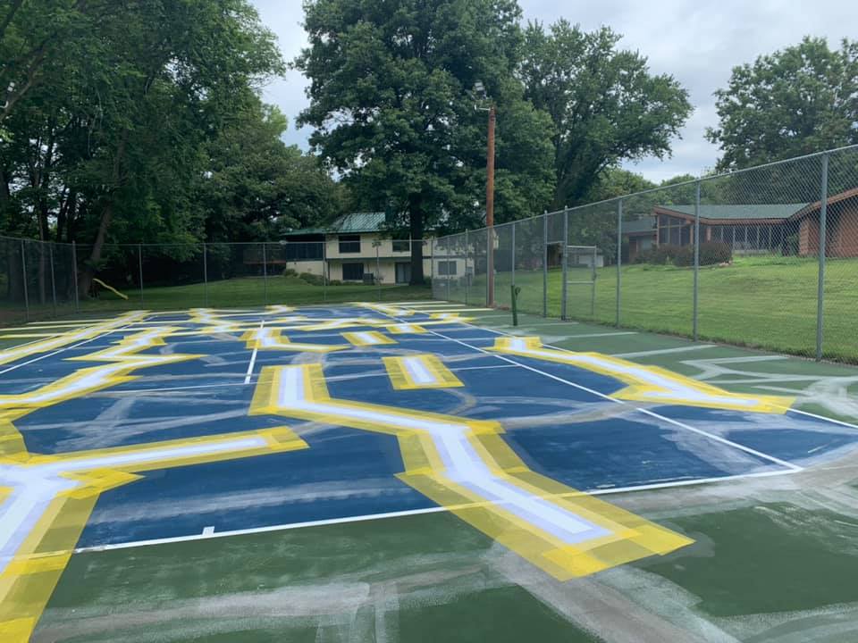 Tennis court crack repair preparation with marked surface areas for renovation planning.